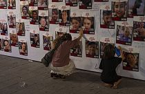 Des Israéliens devant les portraits des otages. 