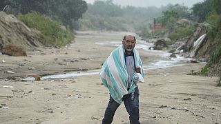 A man walks on the mud caused by hurricane Norma in San Jose del Cabo, Mexico, Saturday, Oct. 21, 2023. Norma