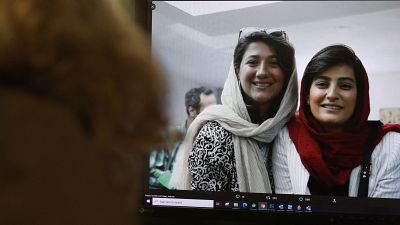 A woman looks at a picture of Iranian reporters Niloufar Hamedi and Elahe Mohammadi 