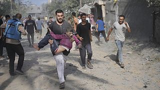 Homem palestiniano transporta rapaz ferido durante bombardeamento de Israel à Faixa de Gaza