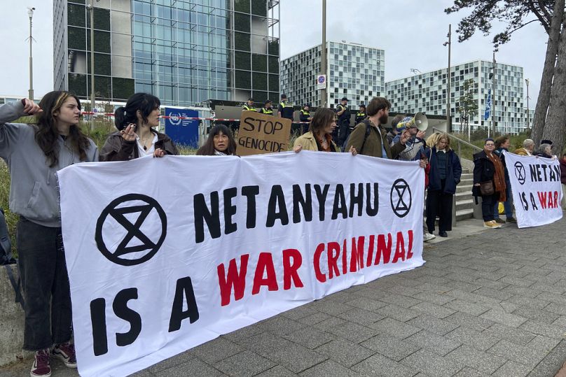 Activists hold up a banner denouncing Israeli PM Netanyahu for Israel’s actions during the war with Hamas, outside ICC at The Hague, 23 October 2023