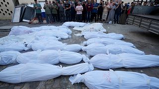 Palestinians pray by the bodies of people killed in the Israeli bombardment of the Gaza Strip in front of the morgue in Deir Al-Balah, Tuesday, Oct. 24, 2023. 