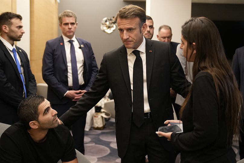 Macron, center, meets with Israeli-French nationals who have lost loved ones, as well as families of hostages, at the Ben Gurion airport, Tuesday, Oct. 24, 2023 in Tel Aviv.