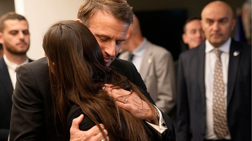 Macron hugs a woman as he meets Israeli-French nationals who have lost loved ones, as well as families of hostages, at the Ben Gurion airport, Tuesday in Tel Aviv.