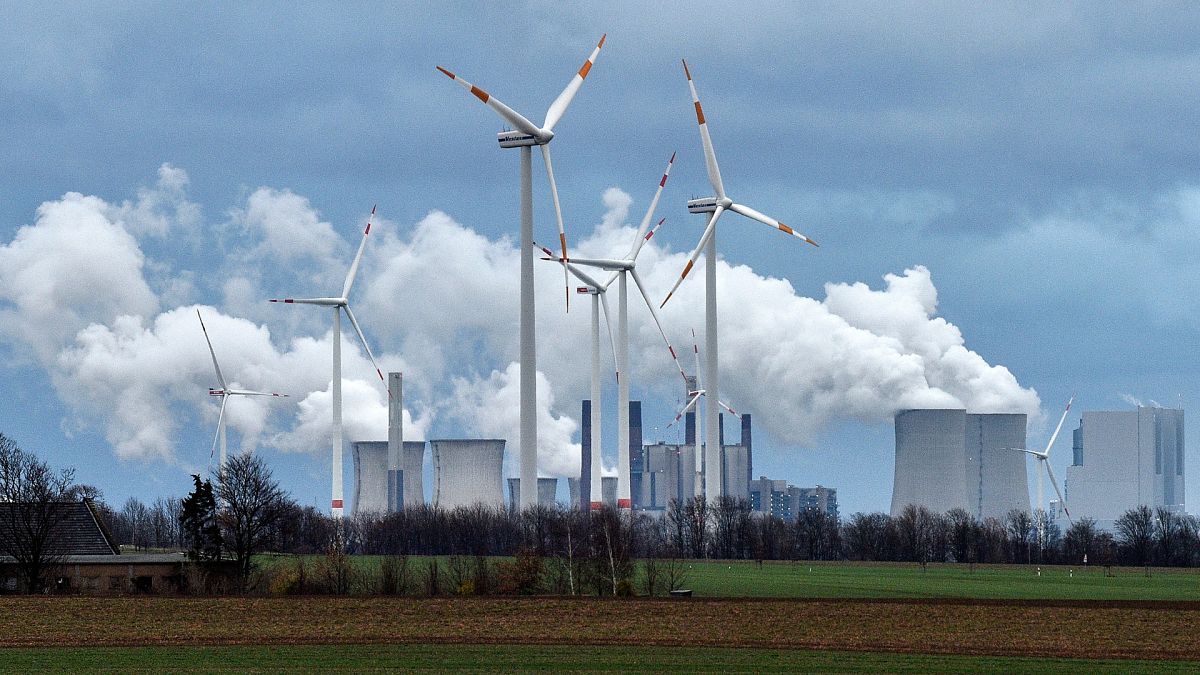 Renewable and fossil-fuel energy is produced when wind turbines are seen in front of a coal fired power plant near Jackerath, Germany.