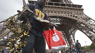 بائع متجول غير قانوني يبيع نسخا بلاستيكية ملونة من برج إيفل في باريس، فرنسا، الاثنين 16 مايو 2016