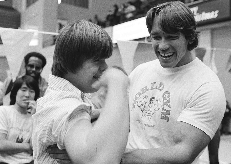 Arnold Schwarzenegger examines John Riley's bicep after assisting him with 50 pushups at a Special Olympics Celebrity Clinic in Washington, D.C., on Dec. 10, 1978.