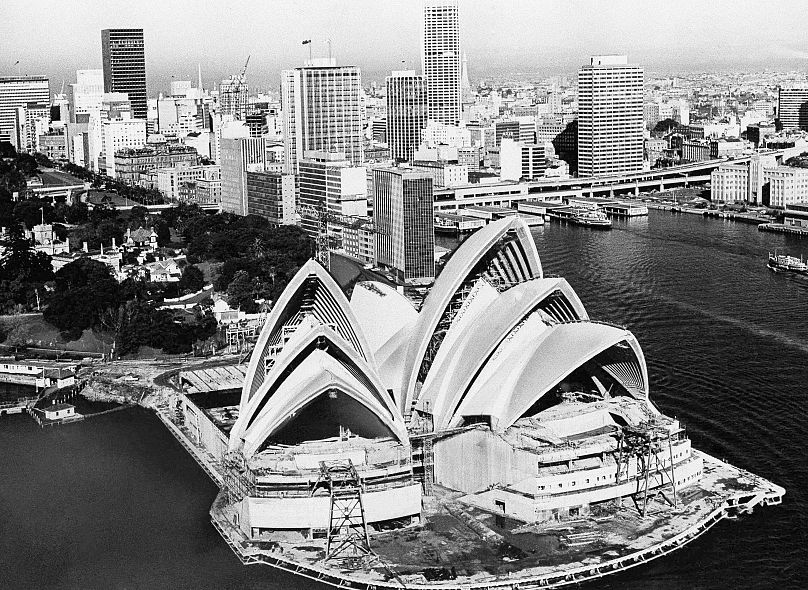 The huge shell-shaped roof of the newly constructed Sydney Opera House on 1 August 1967 in Sydney, Australia, rises before the city's skyline.