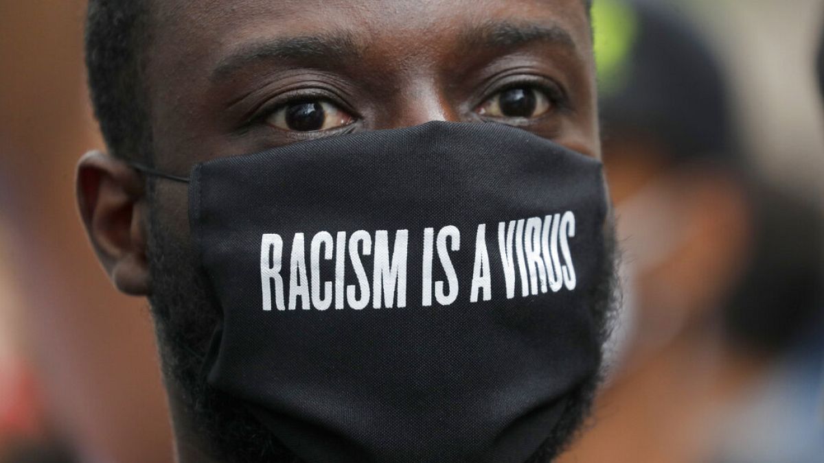 FILE - A protester wears a face mask in front of the US embassy, during the Black Lives Matter protest rally in London, Sunday, June 7, 2020.
