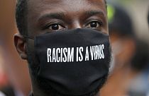 DOSSIER - Un manifestant porte un masque devant l'ambassade des États-Unis, lors du rassemblement de protestation Black Lives Matter à Londres, dimanche 7 juin 2020.
