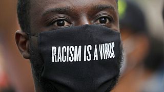 FILE - A protester wears a face mask in front of the US embassy, during the Black Lives Matter protest rally in London, Sunday, June 7, 2020.