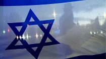 A demonstrator is silhouetted behind a flag of Israel during a rally in support of Israel on Oct. 9, 2023, in Bellevue, Washington.