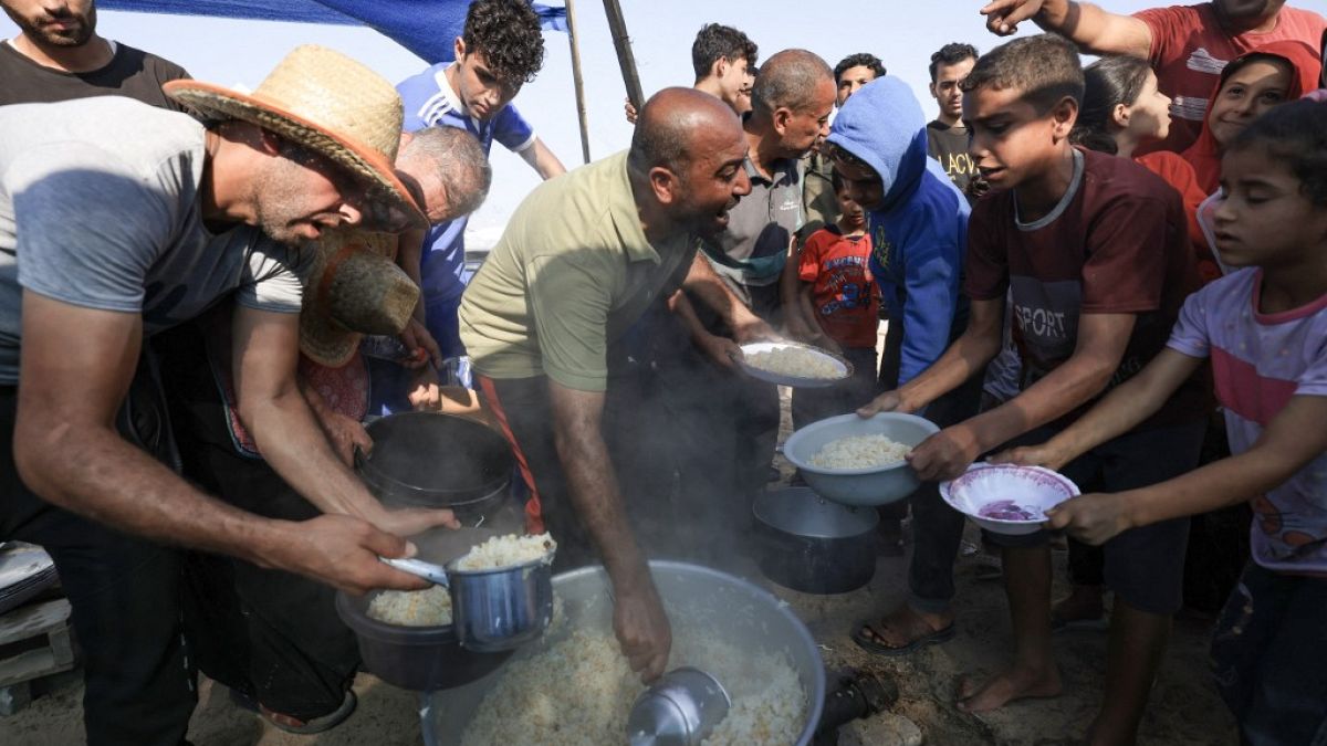Ciudadanos gazatíes hacen cola para una ración de comida. 