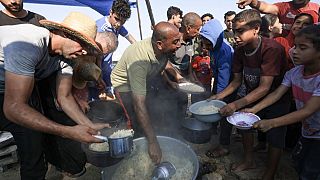 Ciudadanos gazatíes hacen cola para una ración de comida. 