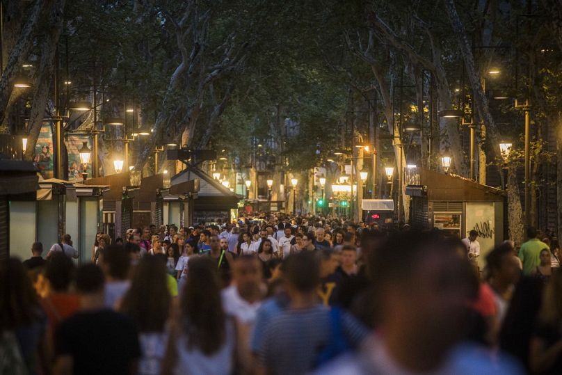 Des personnes traversent la rue historique de Las Ramblas un jour après l'attaque terroriste, à Barcelone, Espagne, vendredi 18 août 2017