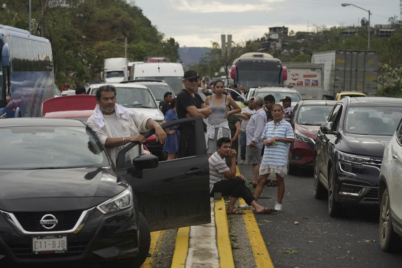 People wait for repair crews to unclog the roads after Hurricane Otis ripped through Acapulco, Mexico, Wednesday, Oct. 25, 2023