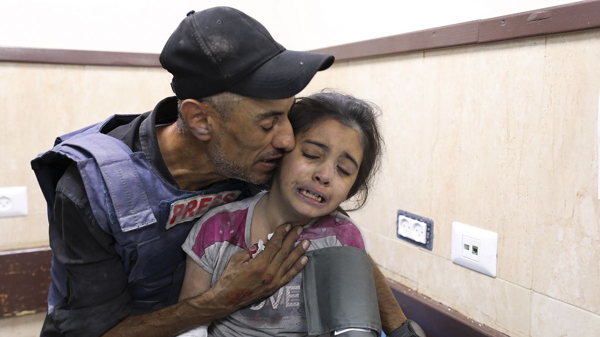 صحفي فلسطيني يواسي ابنة أخيه التي أصيبت في غارة إسرائيلية على منزل عائلتها في مخيم النصيرات للاجئين