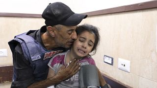 صحفي فلسطيني يواسي ابنة أخيه التي أصيبت في غارة إسرائيلية على منزل عائلتها في مخيم النصيرات للاجئين