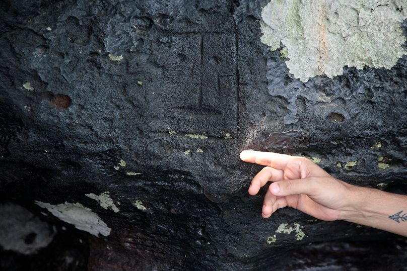 El arqueólogo Jaime de Santana Oliveira señala una antigua talla de piedra, expuesta después de que los niveles de agua cayeron a mínimos récord durante la sequía en Manaus.