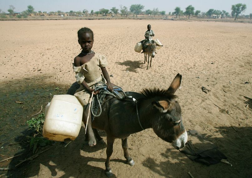 A Sudanese girl rides a donkey on her way to collect water supplies in the West Darfur town of Mukjar, April 2007