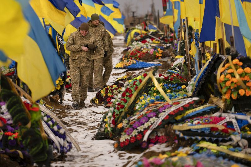 Ukrainian soldiers walk by the graves of fellow soldiers in Kharkiv, Ukraine, Thursday, Feb. 16, 2023.