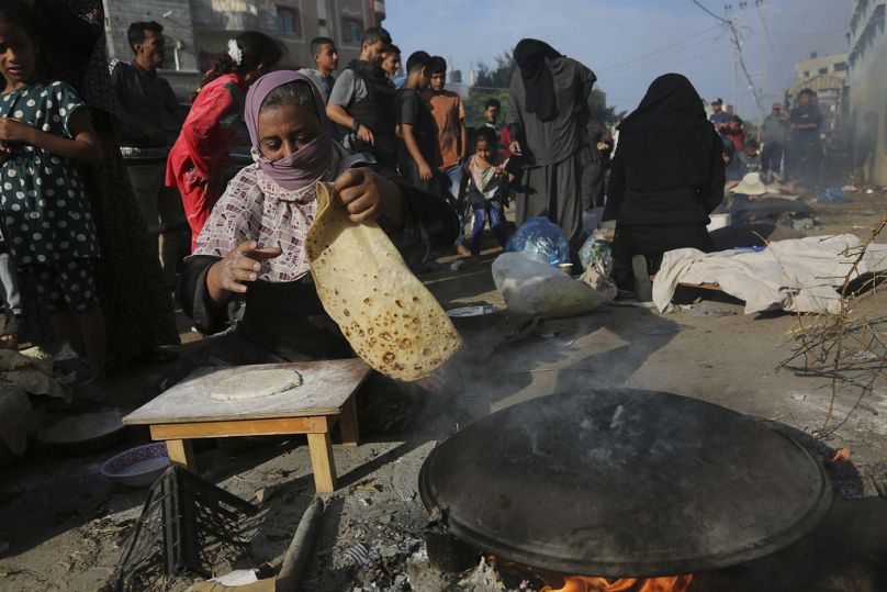 Палестинские женщины пекут хлеб на улице в секторе Газа. 27 октября 2023.