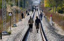 Migrants walk on the railway tracks near a border line between Serbia and Hungary, near the village of Horgos, Serbia, on Oct. 20, 2022.