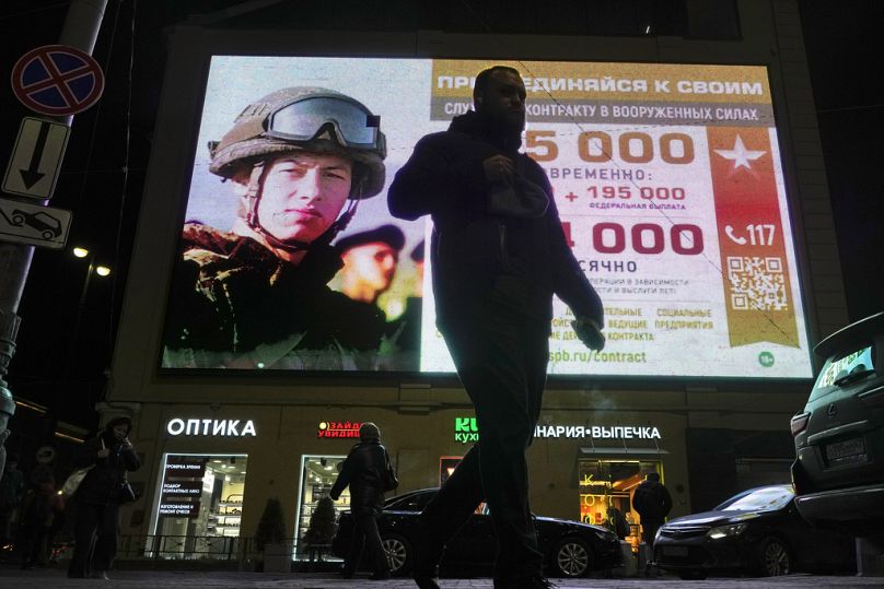 A man walks past an advertising screen depicting Russian army soldiers and promoting contract military service in the Russian army in St. Petersburg, October 2023