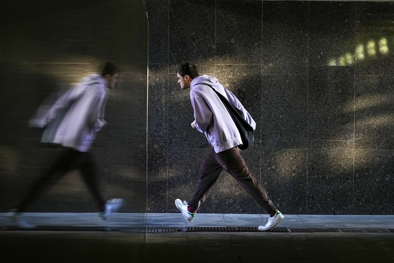 A pedestrian walks along an underground passage reflected in a marble wall in Moscow, September 2023