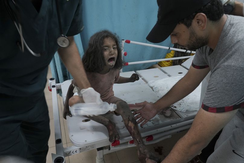 A romok alől kimenekített, sebesült kislány ellátása a Gázai övezetben 2023. október 27-én