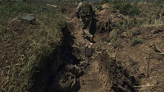 Bir Ukrayna askeri, Donetsk bölgesindeki Bakhmut yakınlarındaki cephe hattında, ölü Rus askerleriyle birlikte yeni ele geçirilmiş bir Rus siperine giriyor