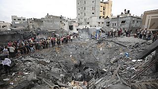 فلسطينيون يتفقدون أنقاض مبنى مدمر بعد غارة جوية إسرائيلية في دير البلح، قطاع غزة، الجمعة 27 أكتوبر 2023.