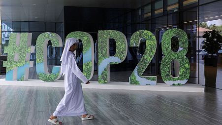 A person walks past a "#COP28" sign during an event in Abu Dhabi, United Arab Emirates, 1 October 2023. 
