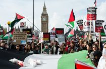 Demonstrators carry a Palestinian flag as tens of thousands of protesters march in London in solidarity with the Palestinian people and to demand an immediate ceasefire