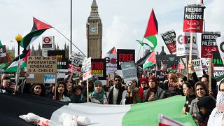 Demonstrators carry a Palestinian flag as tens of thousands of protesters march in London in solidarity with the Palestinian people and to demand an immediate ceasefire