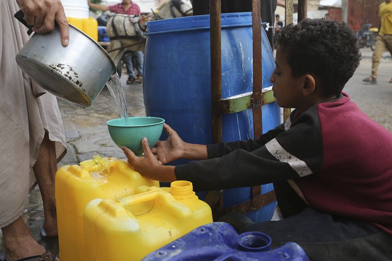 فتى فلسطيني يملؤ الماء داخل غالونات في غزة