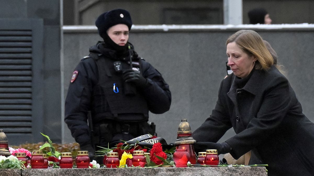 Um policia vigia enquanto a embaixadora dos EUA na Rússia, Lynne Tracy, deposita flores na grande pedra das ilhas Solovetsky, em homenagem às vítimas dos Gulag