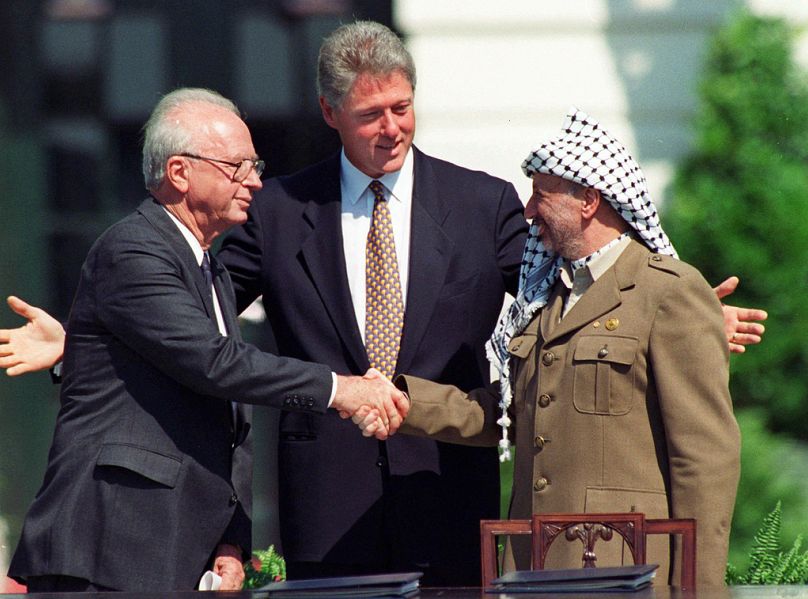 Dönemin İsrail Başbakanı İzak Rabin ile Filistin lideri Yaser Arafat, İsrail'le Filistinliler arasındaki barış anlaşmasının imzalanması münasebetiyle el sıkışırken, 1993