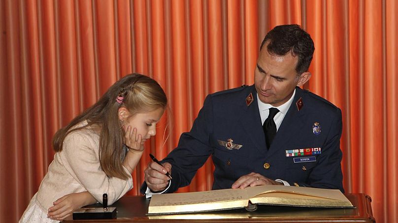 Leonor de Borbón watches as her father King Felipe signs a book