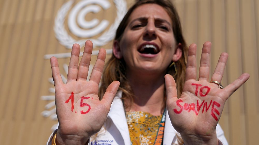 Демонстрантка показва ръцете си които четат 1 5 за оцеляване на