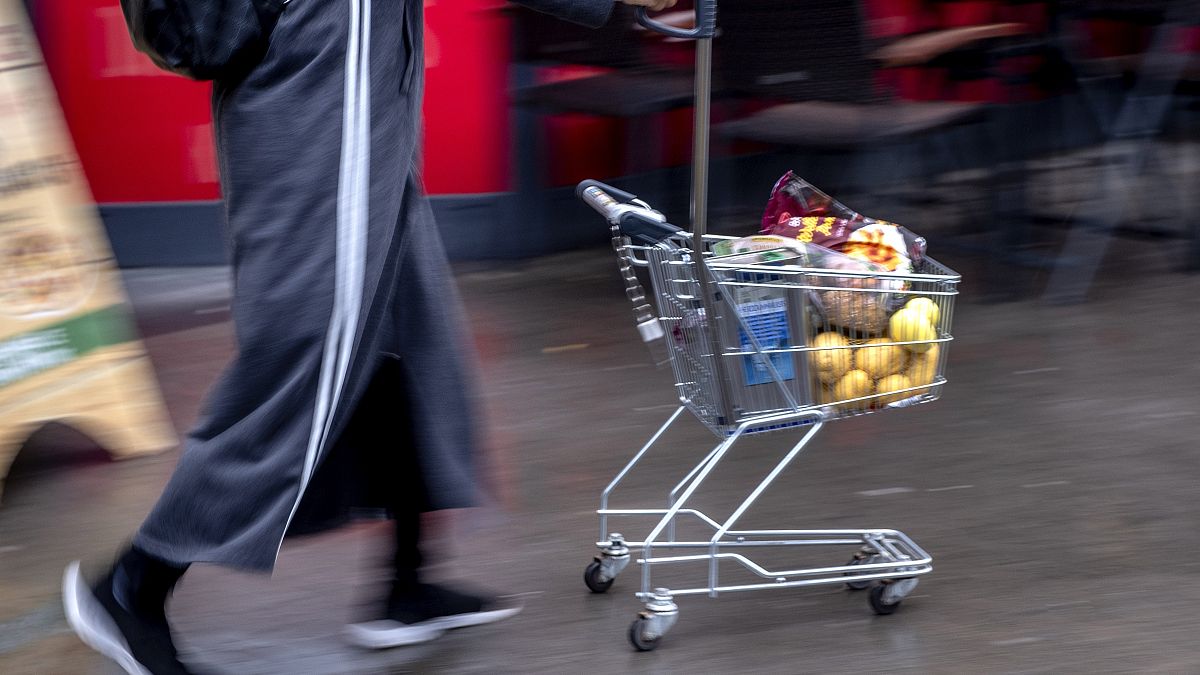 A woman pushes a small shopping cart outside a discount market in Frankfurt, Germany, Thursday, July 27, 2023. 