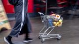 A woman pushes a small shopping cart outside a discount market in Frankfurt, Germany, Thursday, July 27, 2023. 