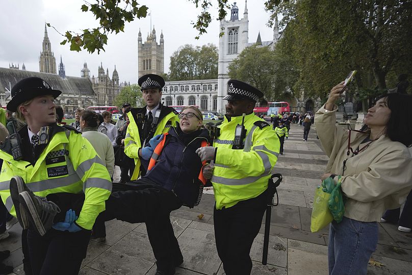 An activist from Just Stop Oil is carried away by police officers as they slow the traffic.