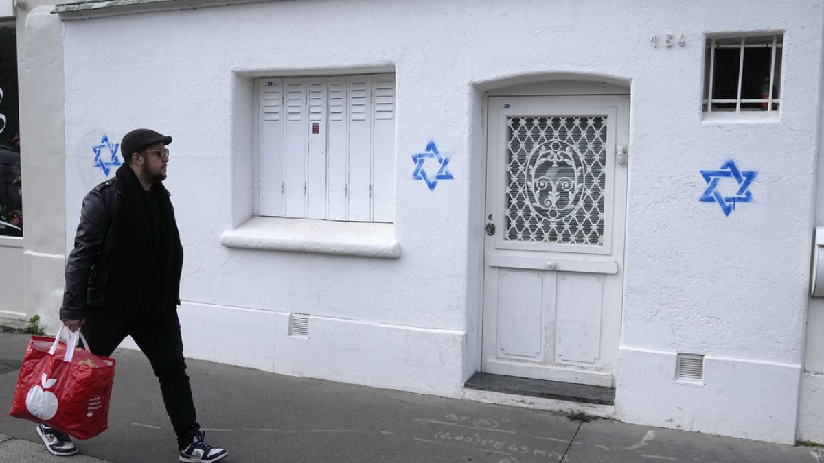 A man walks by Stars of David tagged on a wall Tuesday, Oct. 31, 2023 in Paris. 
