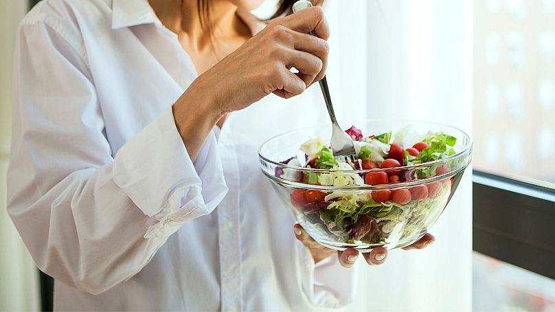 A woman eating a salad from a bowl.