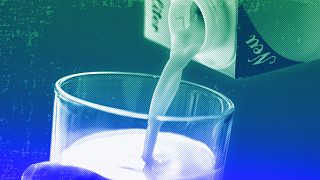 A person pours milk into a glass