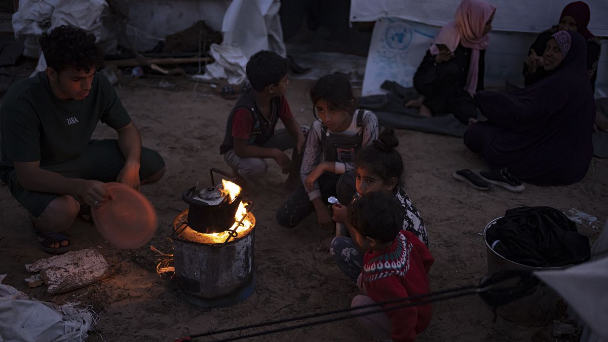 فلسطينيون نزحوا بسبب القصف الإسرائيلي يجلسون بجوار النار في مخيم بخان يونس