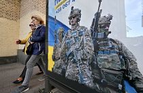 Pedestrians walk past a poster depicting Ukrainian servicemen and a slogan which reads "Bring the victory soon" in Kyiv, on 31 October