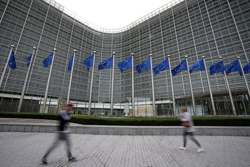 European Union flags flap in the wind as pedestrians walk by EU headquarters in Brussels, September 2023