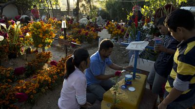 عائلة  مكسيكية خلال احتفالات يوم الموتى في مقبرة سان فيليبي ديل أغوا في أواكساكا، المكسيك.